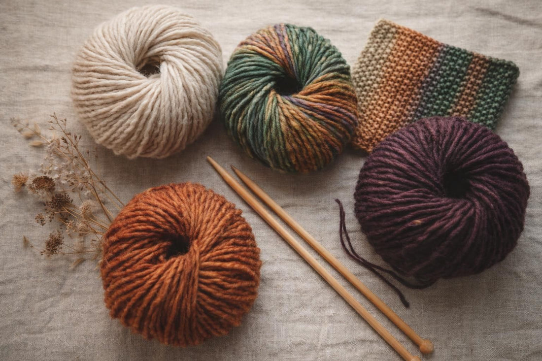 Photo à plat de pelotes de laine et d'aiguilles à tricoter — burda STRICKEN 03/2026 : neuf modèles avec Lang Yarns