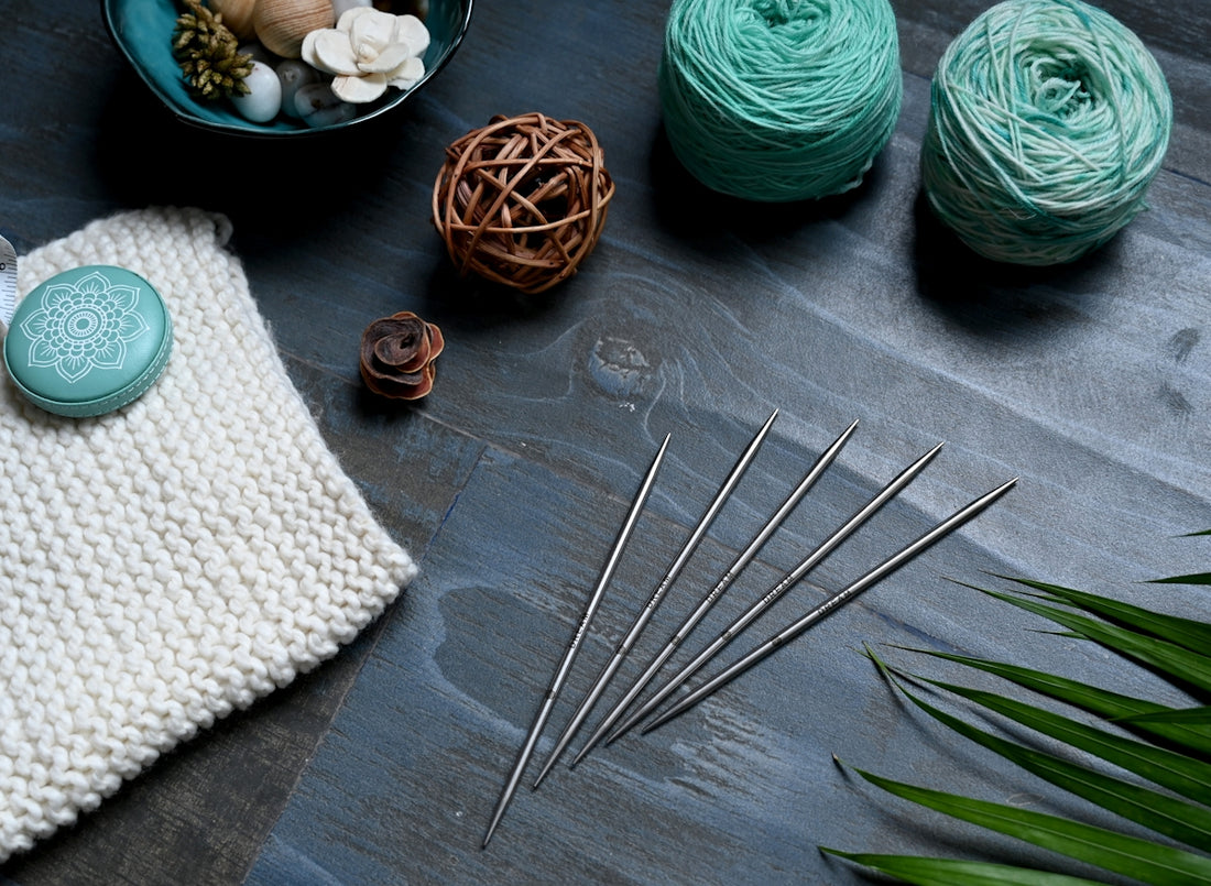 a table topped with yarn and knitting needles